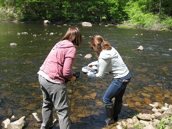 Volunteer receiving training in use of a water quality meter on the bank of a river.